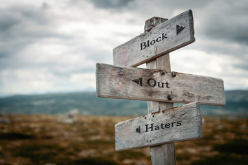 Block out haters text on wooden rustic signpost outdoors in nature/mountain scenery.