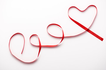 top view of heart-shaped red ribbon on white