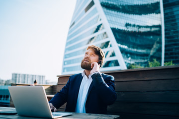 Businessman looking up while speaking on cellphone in megapolis