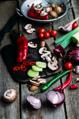Raw vegetables  on a wooden table. Healthy nutrition. Leek, blue onion, champignons, hot pepper, sweet pepper, tomatoes