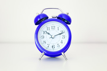 blue round analog alarm clock on white background. time 10:10. classic blue color 2020