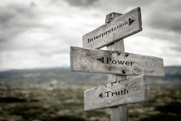 Interpretation, power and truth text on wooden rustic signpost outdoors in nature/mountain scenery....