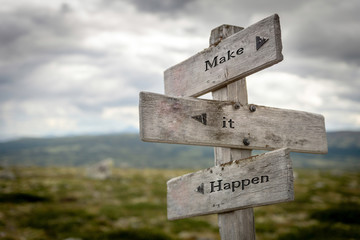 Make it happen text on wooden rustic signpost outdoors in nature/mountain scenery. Goals, future...