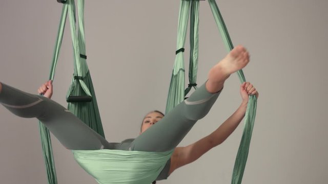 Yoga master in aerial yoga hammock demonstrate an element falling down and lift up her legs