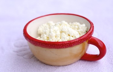 Clay cup with red rim and curd white fresh inside cup side view