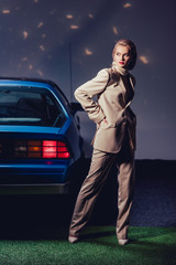attractive and stylish woman in suit standing retro near car
