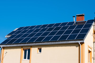 Fototapeta premium Solar panel system on house roof, sunny blue sky background.Blue solar panels. 