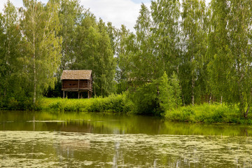 Obraz premium Rural landscape. Sheds for storage of agricultural goods are located on the river Bank among the birches. Kostroma, Russia.