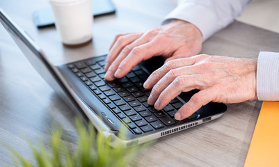 Hands typing on laptop keyboard