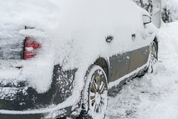 Snow-covered machine. Car under the snow. Lots of snow and big snowdrifts on the street. Vehicles are completely covered in snow. Cold winter weather