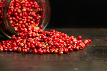 Pimienta roja en granos dentro de un cuenco de cristal sobre mesa de metal rústica. Vista de frente y de cerca. Concepto Dark Food