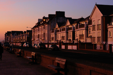 Fototapeta premium Seafront street with houses at sunset in Seaford, United Kingdom.