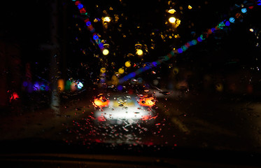 Abstract painterly rain drops on a car window with vibrant city and street lights out of focus in the background. Tired and drunk driving in wet and rainy conditions. safe driving.