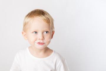 Portrait of fair-haired boy with chocolate on his face isolated on white.