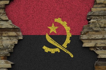 Angola flag depicted in paint colors on old stone wall closeup. Textured banner on rock wall...
