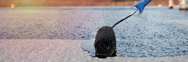 Worker applies bitumen mastic on the foundation