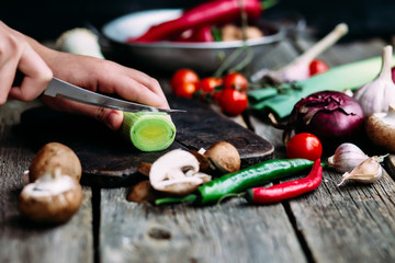 Female hands cut vegetables on the board. Cooking vegetarian food.