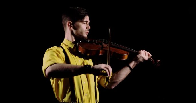 Man professional violinist plays alt or violin on black background, front view. Guy musician emotionally playing solo on alt. Elegant person performs classical composition on fiddlestick instrument.