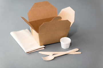 package, recycling and eating concept - disposable box for takeaway food with wooden fork, knife...