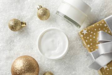 Jar of winter cream, gift boxes for skin on snowy background, space for text. Top view