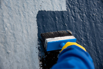 Worker applies bitumen mastic on the foundation