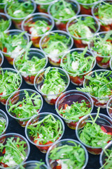 Fototapeta na wymiar Mini appetizer salad in a glass of tomatoes with mozzarella, arugula and pesto. Italian traditional food for guests and participants at the event. Catering and guest services.