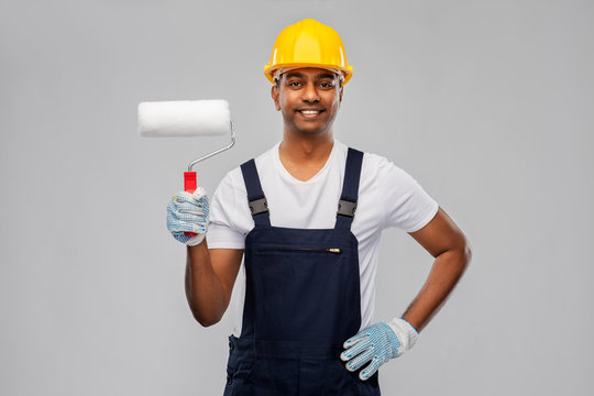 repair, construction and building - happy smiling indian builder or painter in helmet with paint roller over grey background