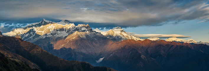 Panoramic view of the majestic Himalayan peaks - Annapurna IV and Annapurna II, covered with clouds illuminated by the sunset. View from the Korchon hut.