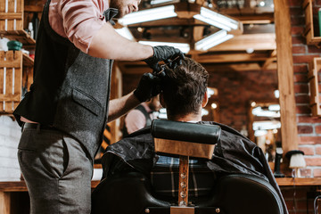 Fototapeta na wymiar bearded barber cutting hair of man in barbershop