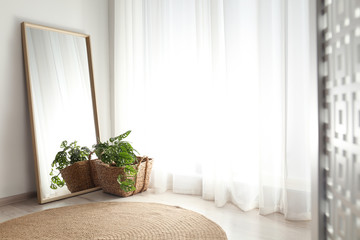 Large mirror with wooden frame near window in light room
