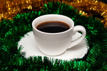 New Year coffee in little white cup and tinsel around. Christmas espresso
