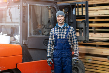 Fototapeta na wymiar Young male worker driving forklift in lumber yard