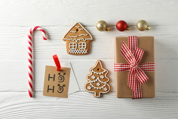 Flat lay composition with tasty homemade Christmas cookies, gift box, candies, toys on white wooden background, space for text. Top view