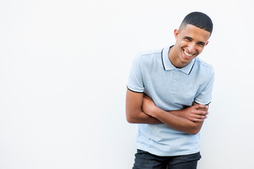 young North African man laughing by white background with arms crossed and looking away