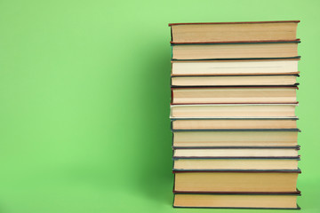 Stack of hardcover books on green background. Space for text