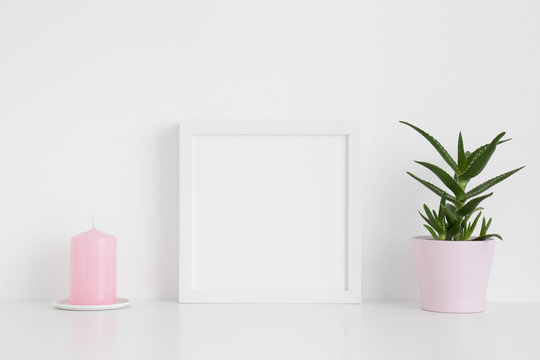 White square frame mockup with a aloe vera in a pot and a candle on a white table.