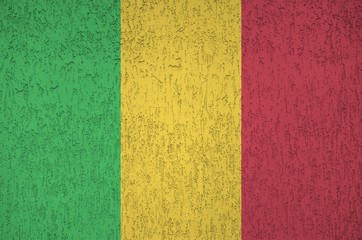 Mali flag depicted in bright paint colors on old relief plastering wall. Textured banner on rough...