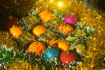 Fototapeta na wymiar Christmas balls, gift boxes and tangerines on tinsel