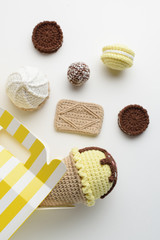 Handmade knitted amigurumi toys. Lemon and chocolate play ice cream, cookies and bites. Crochet miniature stuffed sweets on white background