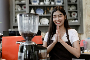 Beautiful smiling girl barista give pay to customer or welcome, respect, hello to someone. It is a Thai culture. She look friendly, Small business owner and work concept.