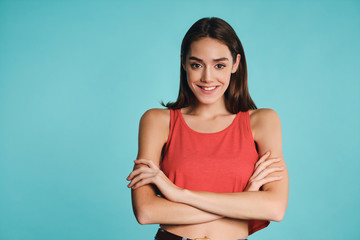 Obraz premium Pretty smiling casual girl holding hands crossed confidently looking in camera over colorful background isolated