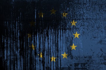 European union flag depicted in paint colors on old and dirty oil barrel wall closeup. Textured...
