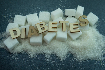 Selective focus of sugar cubes and wood letter word 'DIABETES' on black background. Illness and...