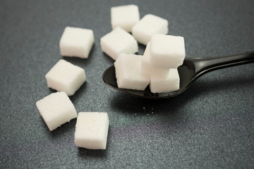 Selective focus of sugar cubes on spoon. Illness and diabetes concept.