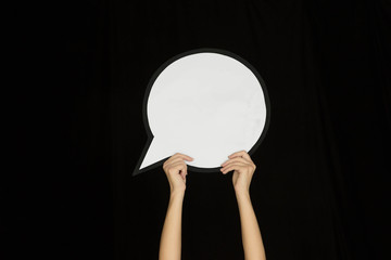 Hands holding the sign of comment on black studio background. Negative space for text or image, advertising. Social media, showing meaning, communication, gadgets, modern technologies. Speech bubble.