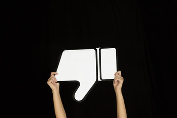 Hands holding the sign of dislike on black studio background. Negative space to insert your text or image, advertising. Social media, showing meaning, communication, gadgets, modern technologies.