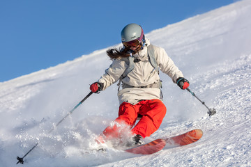 Girl On the Ski. a skier in a bright suit and outfit with long pigtails on her head rides on the...