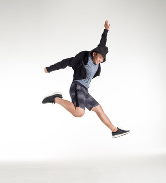 In a white background studio texture copy space image, a young man wears a hood hiphop, black sneakers, jumps moving dance on the wavy, for example workout exercise  sport to have fun and enjoy life.