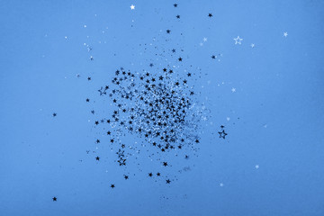 Star sparkles on classic blue background. Christmas and New year concept. Festive color backdrop with copy space