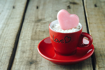 Pink heart shape on red coffee cup with wood table background ,vintage love concept.